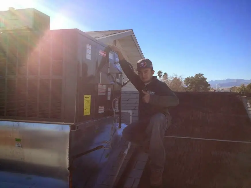 HVAC technician performing Air Duct Cleaning on a rooftop unit in Sidney